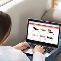 Eine Frau sitzt vor ihrem Laptop und schaut online nach Schuhen