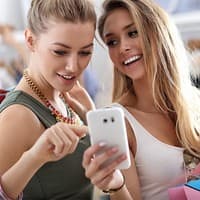 Zwei junge Frauen schauen zusammen auf ein Handy